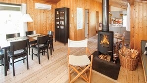 A cozy cabin interior with a dining area, a kitchen, and a wood-burning stove. - Stunning home in Samsø with WiFi (Samsø)