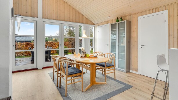 A dining area with a round table, chairs, a rug, and a view of the outdoors through large windows. - Beautiful home in Haarby with WiFi (Haarby)