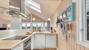 A modern kitchen with white cabinetry, a stainless steel range hood, a Bosch dishwasher, and wooden flooring. - Beautiful home in Haarby with WiFi (Haarby)