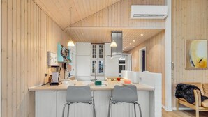 A modern kitchen with white cabinetry, a central island with bar stools, and a hanging light fixture. - Beautiful home in Haarby with WiFi (Haarby)