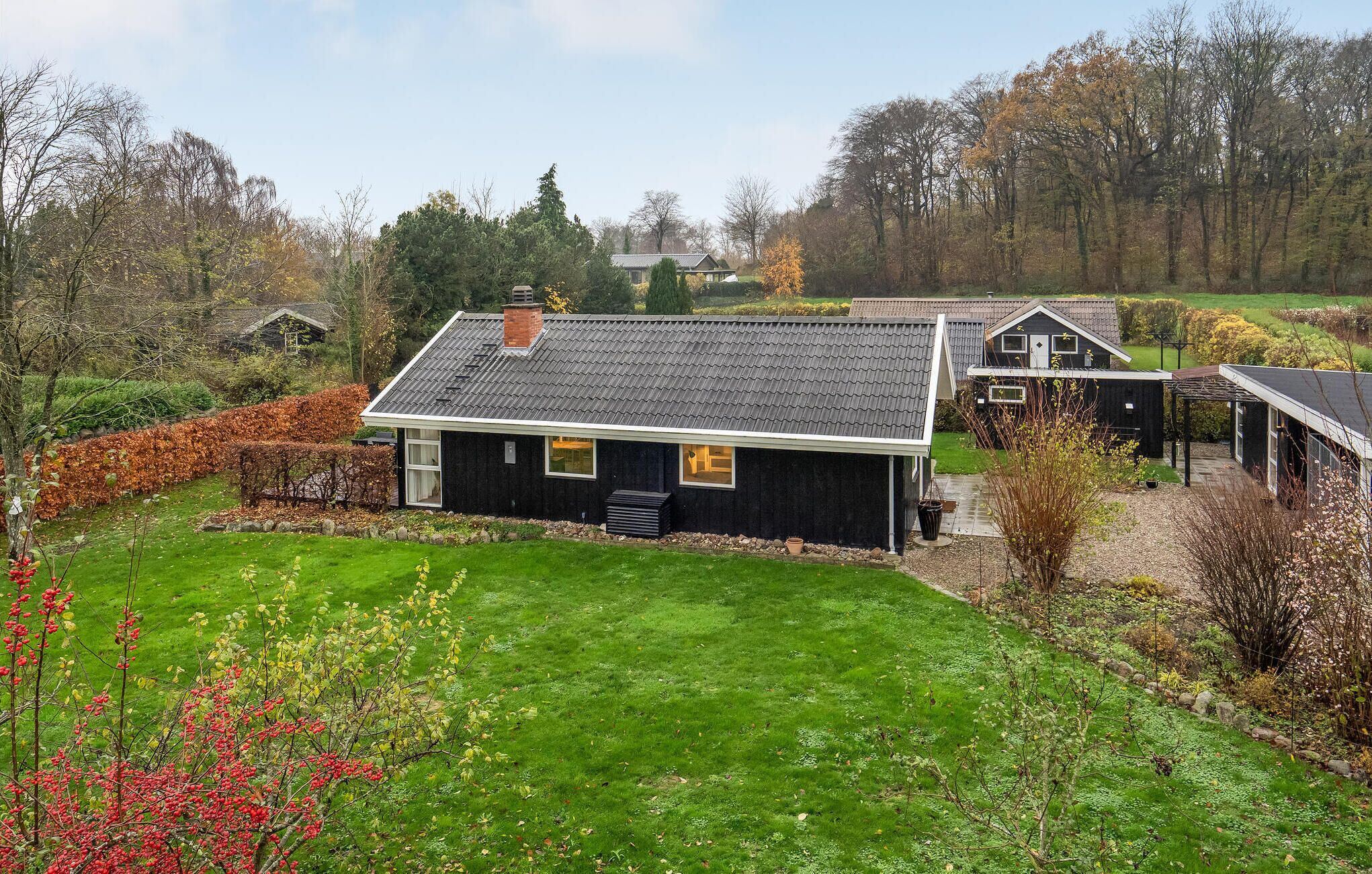 A residential property with a large lawn, a house with a dark exterior, and a garage.