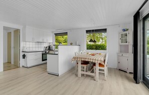 Modern kitchen with oven and dining area for four, offering a view of lush greenery.