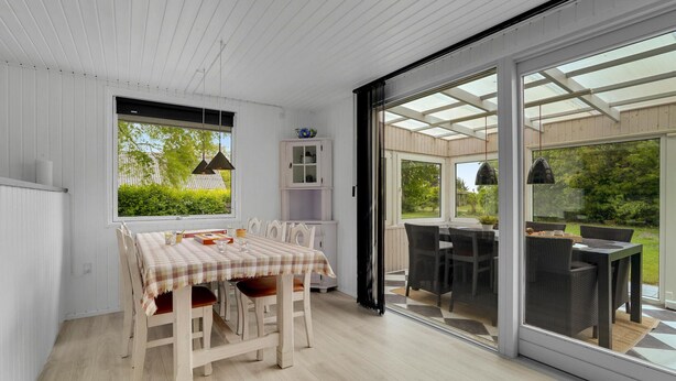 A dining area with a table set for four, a white cabinet, and a view through a glass door to an outdoor patio.