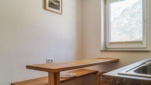 Uma cozinha com um banco de madeira, uma janela e vista para as montanhas, além de uma pia.