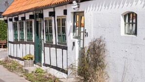Een traditioneel gebouw met een witte gevel, groene luiken en een dak met rode dakpannen.