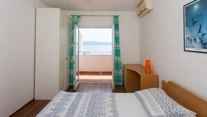 A bedroom with a bed, a desk, a chair, a window with curtains, and a view of the sea. - 2 bedroom cozy apartment in Suhi Potok, Jesenice (Suhi Potok, Jesenice)