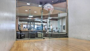 Et fitnesscenter med basketballbane, styrkeudstyr og en trappe til en etage over.