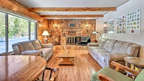Ein gemütliches Wohnzimmer mit Kamin aus Stein, Ledersofas und einem großen Holztisch.