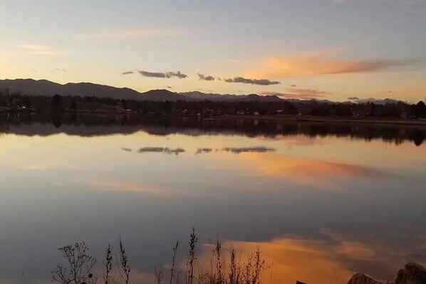 Un lac paisible, avec des montagnes en arrière-plan et un ciel dégagé.
