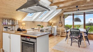 A modern kitchen with a central island, built-in appliances, and a dining area with a view. - Nice home in Kalundborg with WiFi (Kalundborg)