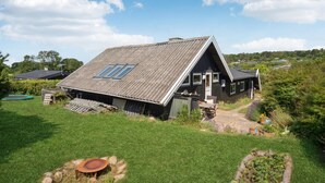A wooden house with a sloped roof and skylights, surrounded by a well-maintained lawn and garden. - Nice home in Kalundborg with WiFi (Kalundborg)