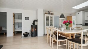 Een moderne keuken met een centraal eiland, witte kastjes en een eethoek met houten stoelen.