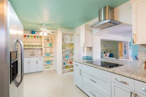 Una cocina moderna con armarios blancos, un refrigerador de acero inoxidable y una estufa empotrada.