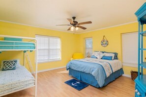 Un dormitorio con una litera, una cama individual, un ventilador de techo y una pared de acento azul.
