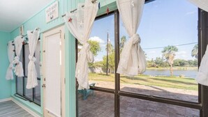 Une pièce avec vue sur un lac, une porte avec une pancarte et des rideaux attachés à la fenêtre.