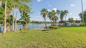Une propriété au bord du lac, dotée d’une pelouse verdoyante, de palmiers et d’une maison avec un quai.