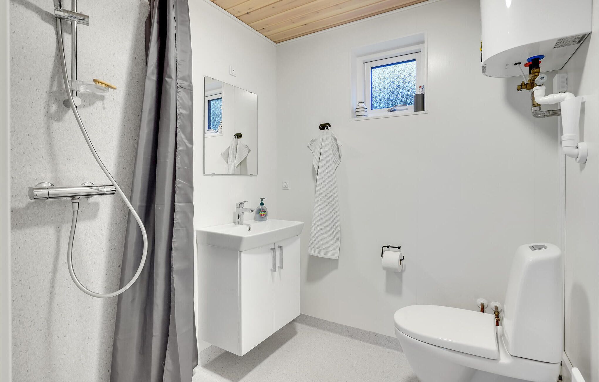 Ein modernes Badezimmer mit Dusche, Waschbecken, Toilette und einem kleinen Fenster.
