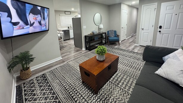 Een woonkamer met een televisie, bank, salontafel en een rug met patroon.