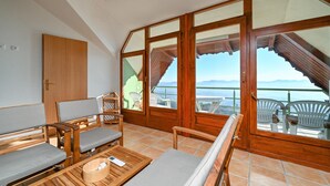 Een balkon met houten meubilair, uitzicht op bergen en een betegelde vloer.