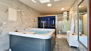A modern bathroom with a large bathtub, a glass shower enclosure, and a vanity with a mirror. - Stunning home in Madzarevo with sauna (Madzarevo)