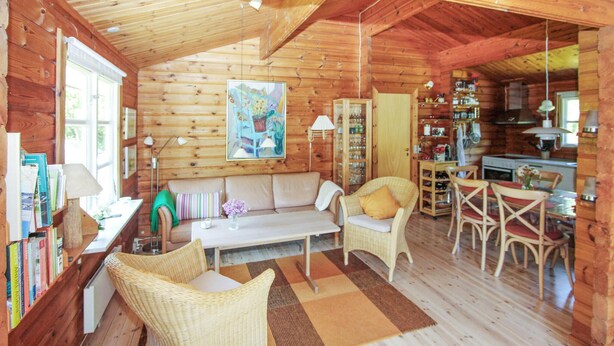 Un intérieur chaleureux de chalet en bois, comprenant un espace de vie, un coin repas et une cuisine.