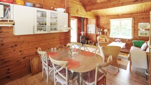 Un chalet confortable avec un intérieur en bois, une table à manger avec des chaises, une cheminée et une bibliothèque.