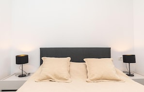 Simple, stylish room with a single bed and two floor lamps.
