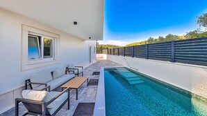 Un área junto a la piscina con un espacio de descanso y una pileta.