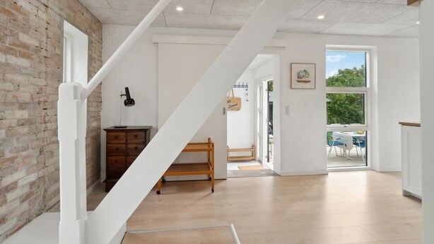 A modern interior with exposed brick walls, a wooden bench, a desk with a lamp, and a view through a glass door to an outdoor area. - 3 bedroom stunning home in Samsø (Samsø)