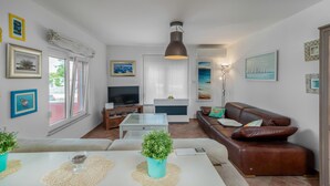 Una sala de estar con sofá, televisor y zona de comedor con mesa y sillas.