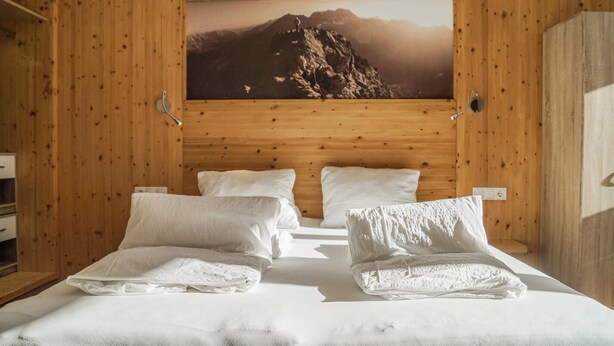 A wooden-paneled room with a bed, pillows, and a framed picture of a mountain. - 1 bedroom gorgeous apartment in Längenfeld (Längenfeld)