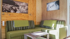 A cozy room with a green sofa and a matching armchair, a wooden wall with a framed picture, and a small table. - 1 bedroom gorgeous apartment in Längenfeld (Längenfeld)