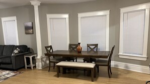A dining area with a wooden table, four chairs, and a bench. There is a gray couch and a small side table with a vase. - Vintage Home in Portage, WI (Portage)