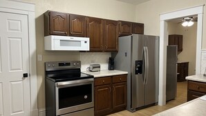 A kitchen with wooden cabinets, stainless steel appliances, and a white microwave. - Vintage Home in Portage, WI (Portage)