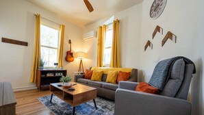 A living room with a sofa, a coffee table, a guitar, and a lamp. - Charming 1BR Basecamp | Close to UofA (Tucson)