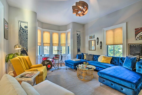 A living room with a blue sofa, yellow armchair, and a drum set. - Walk to Downtown: Pet-Friendly Millerton Home! (Millerton)