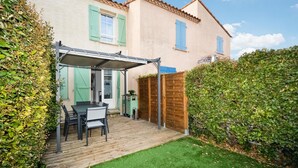 A patio with a table and chairs, a covered area, and a wooden fence. - Cozy home in Aigues-Mortes with WiFi (Aigues-Mortes)