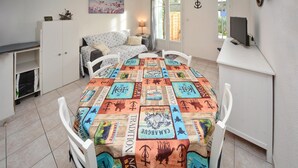 A dining area with a table covered in a patchwork tablecloth featuring various designs and text, surrounded by white chairs. - Cozy home in Aigues-Mortes with WiFi (Aigues-Mortes)