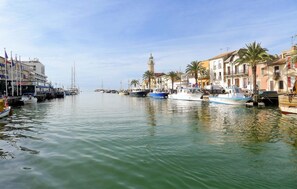 A marina with boats docked along a waterfront, buildings with balconies, and a prominent tower in the background. - Awesome home in Aigues-Mortes with WiFi (Aigues-Mortes)