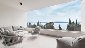 A balcony with a sofa, chairs, and a view of a lake and trees. - Amazing home in Dramalj (Dramalj)