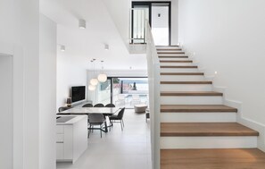 A modern kitchen with a dining area, a staircase, and a view of the outdoors.