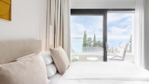 A hotel room with a bed, a balcony with a table and chairs, and a view of the sea. - Amazing home in Dramalj (Dramalj)