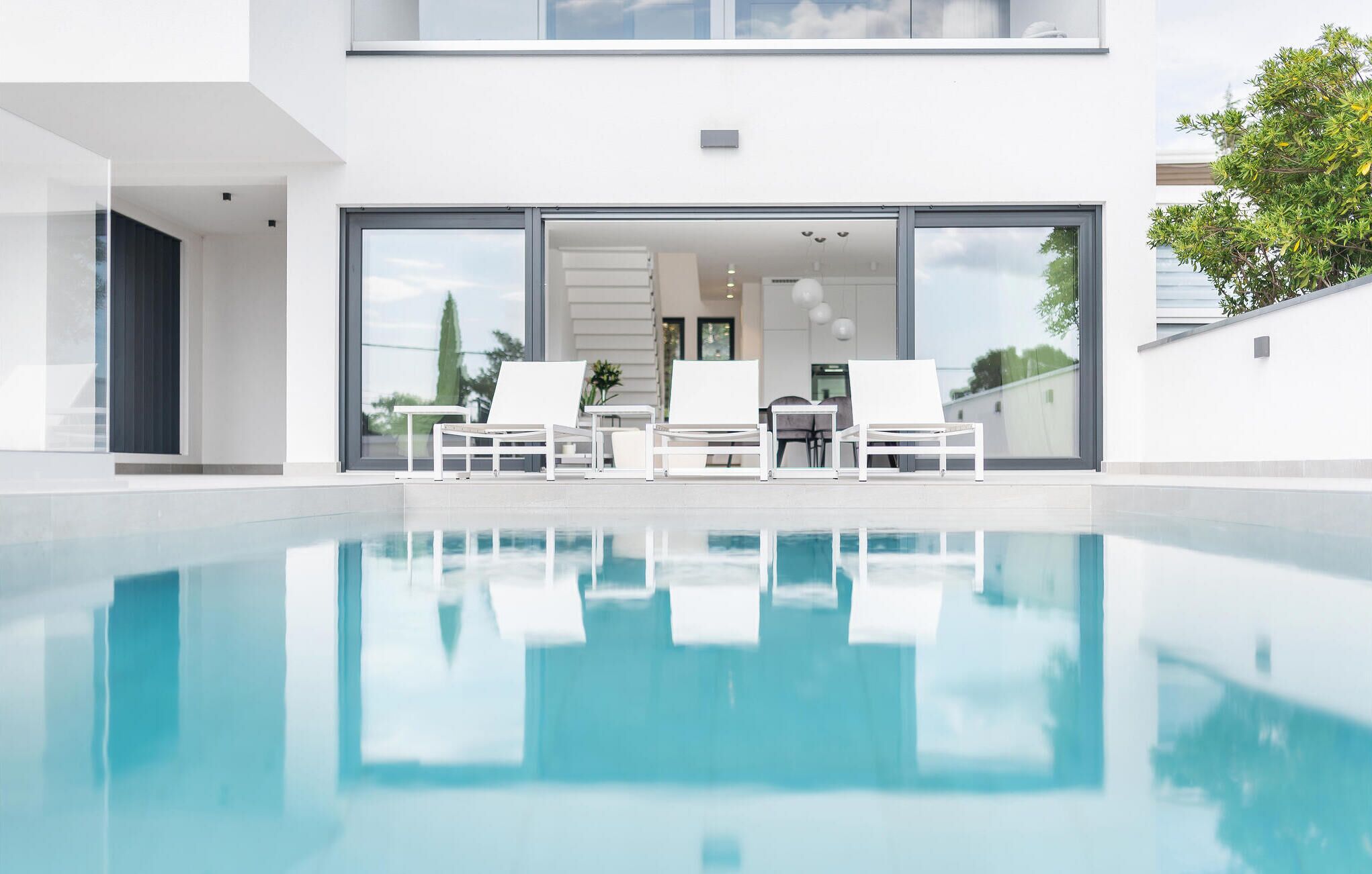 A modern pool area with white lounge chairs and a clear view of the adjacent building.