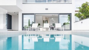 A modern pool area with white lounge chairs and a clear view of the adjacent building. - Amazing home in Dramalj (Dramalj)