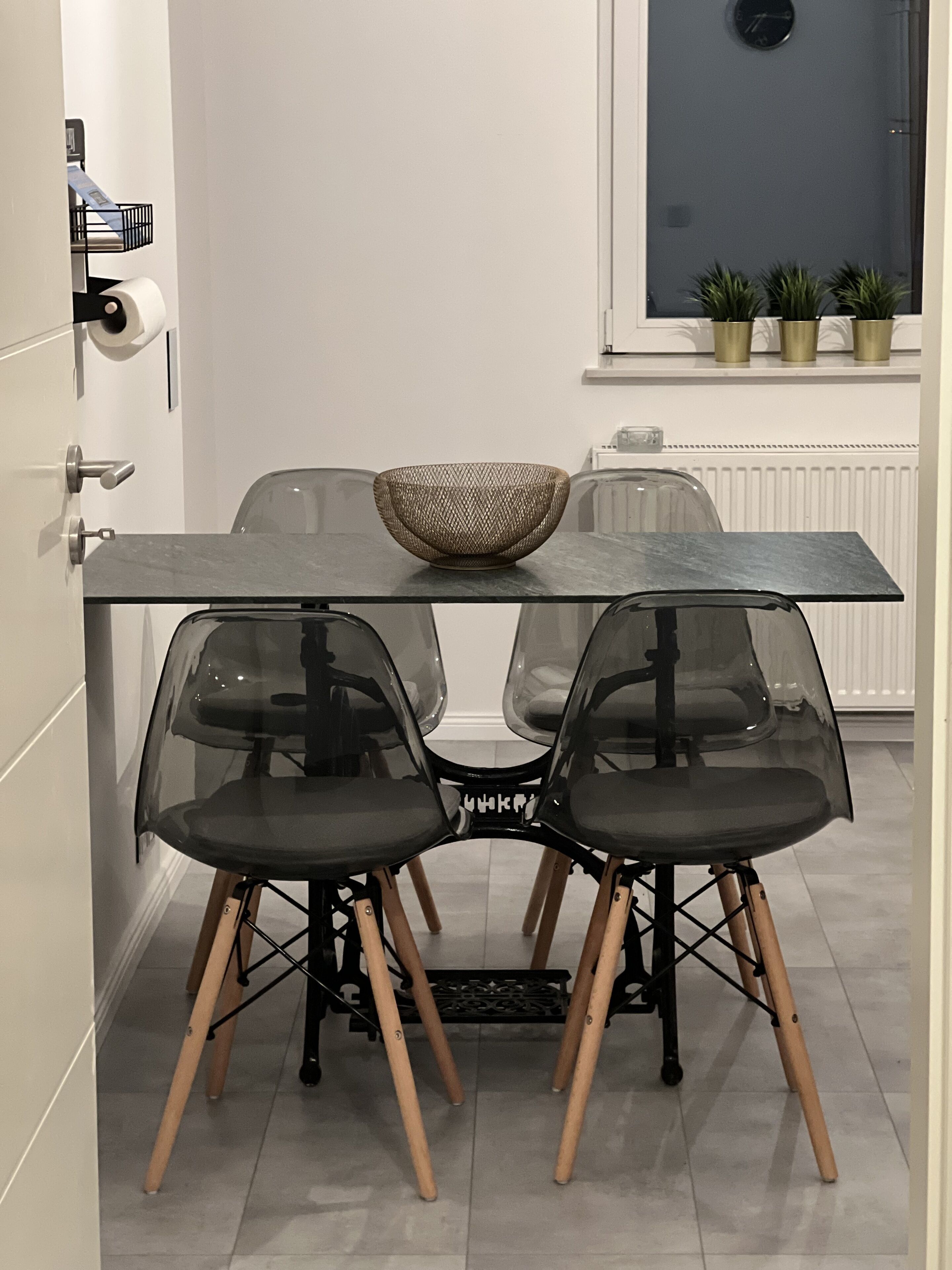 Ein moderner Essbereich mit Glastisch, transparenten Stühlen und einer gewebten Schale als Mittelstück.