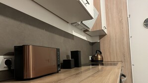 Une cuisine au design moderne, équipée d’une bouilloire en acier inoxydable, d’une machine à café et d’un four à micro-ondes, le tout posé sur un plan de travail en bois.
