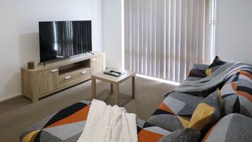 Relax in a spacious bedroom with a large bed, flat-screen TV, and ceiling fan.