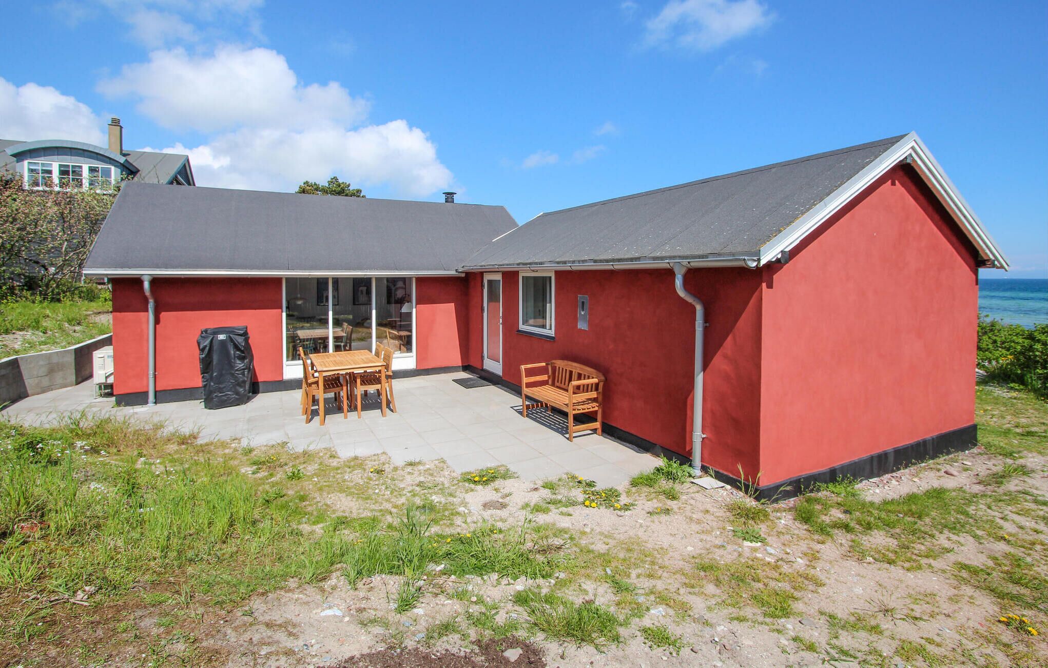 Een rood gebouw met een terras, een tafel en een bank.