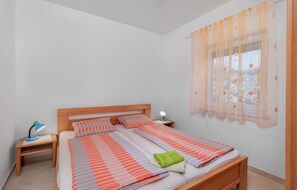 Une chambre à coucher avec un lit en bois, une literie à rayures, une table de chevet avec une lampe et des rideaux en voile.