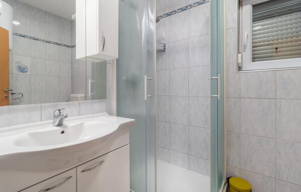 A bathroom with a white sink, a glass shower enclosure, and a yellow toilet. - Beautiful apartment in Ribarica (Ribarica)